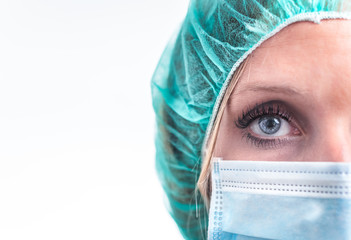 close-up, half a nurse's face with blue eyes, mask and headgear, isolated in a white background.