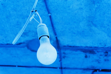 Light bulb on the background of a concrete ceiling. Cold light.Close-up