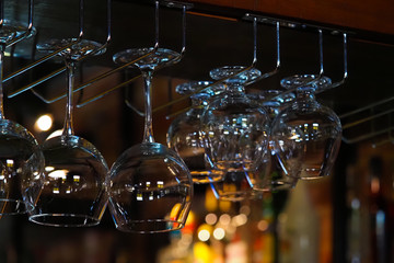 Empty glasses for wine above a bar rack. Hanging glasses in a restaurant