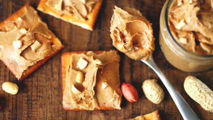 Selective focus. Peanut butter on crackers. Peanuts. A jar of peanut butter. High-calorie breakfast. Delicious snack.