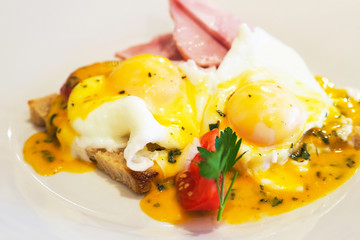 Hearty breakfast,  eggs Benedict. Breakfast of boiled eggs, poached,  with ham on a bun with mustard sauce
