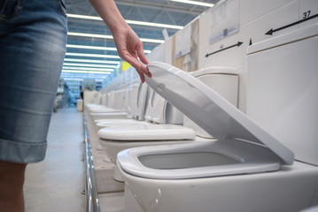Buyer is choosing a new toilet bowl in a home store close up.