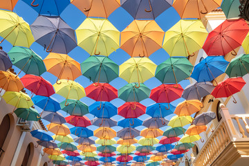 Fototapeta na wymiar The sky is full of colorful umbrellas. Street with umbrellas in the sky in the village San Bartolome de la torre. Summer decoration and sun protection. Huelva province, Andalusia, Spain