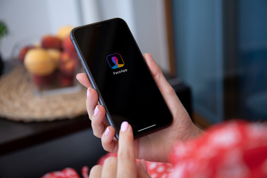  Woman hand holding iPhone 11 with application service FaceApp