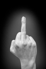 Woman's hand show middle finger on black background. Fuck You, symbol. Black and white tone. offensive gesture