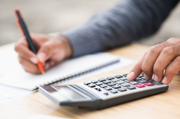 Close up businessman hand using calculator and note information financial administration.