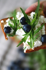 Selective focus. Macro. Toast with cottage cheese, blueberries and arugula in a man's hand. Healthy snack. The keto diet.