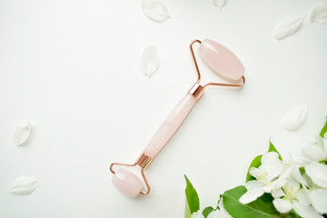 Pink roller face massager and gouache scraper . Rose quartz jade roller on a white background. Anti...