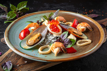 Black pasta with cuttlefish ink with seafood mussels, shrimps, red caviar and basil