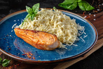Gourmet delicious tagliatelle pasta cooked with cheese sauce and grilled salmon fillet. Balanced nutritious dish. Still life for restaurant poster