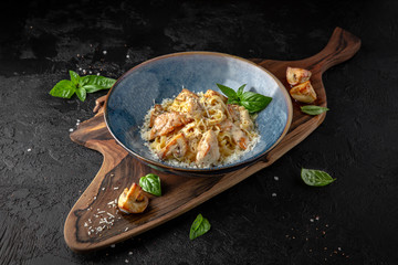 Gourmet delicious tagliatelle pasta cooked with grilled chicken pieces, fried mushrooms and parmesan cheese. Balanced nutritious dish. Still life for restaurant poster