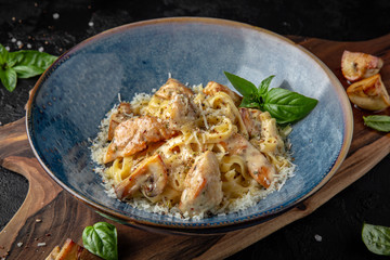 Gourmet delicious tagliatelle pasta cooked with grilled chicken pieces, fried mushrooms and parmesan cheese. Balanced nutritious dish. Still life for restaurant poster