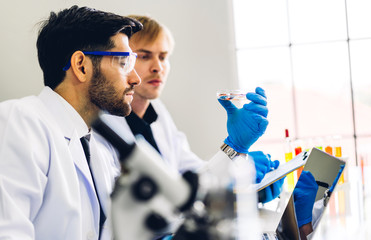 Professional two scientist man research and working doing a chemical experiment while making...