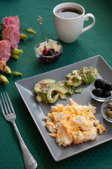 Nutritious breakfast per person: scrambled eggs, olives, olives, avocados, cheese and raspberry jam. 