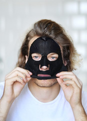   Anti-aging eye therapy.  young man taking care of his undereye wrinkles applying facial mask. man  moisturizing face mask. Cosmetology and skin care concept.