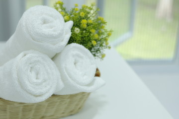 Obraz na płótnie Canvas Roll up white towels in the basket on the table,Spa accessories,Beautiful composition of spa , spa relax concept, herbs for massage, beautiful spa set on wood table,For marketing products