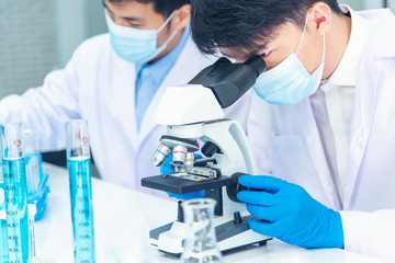 Fototapeta premium Two asian scientist team reserch chemistry science tube experiment biotech antibody sample in laboratory Cultivate Vaccine against covid-19 virus. Scientist consult, analyze in Chemistry Laboratory