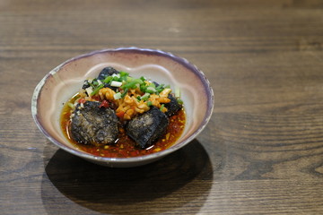 close up a bowl of stinky tofu on retro wooden table. traditional Chinese snack
