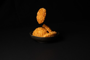 fried crispy rice crackers called rice age with soy,salt sugar etc flavor on black background is a traditional japanese snack.