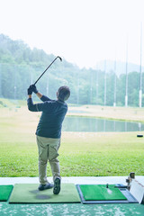 ゴルフ場で練習をするシニアの男性