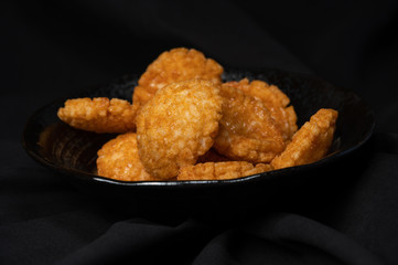 fried crispy rice crackers called rice age with soy,salt sugar etc flavor on black background is a traditional japanese snack.