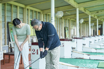 Fototapeta na wymiar ゴルフ場でゴルフを教える男性と教わる女性
