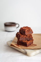 Homemade brownie on marble board and brown paper with coffee in the background