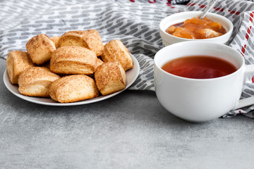 Tasty breakfast. Homemade sweet cinnamon cookies and cup of tea. Apple confiture on background