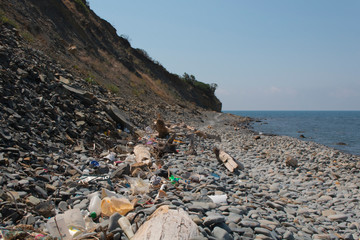 Spilled garbage on the beach. Empty used dirty plastic bottles. Dirty sea sandy shore the Black Sea. Environmental pollution. Ecological problem.