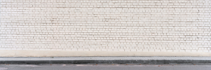 large white brick wall with empty place over street road
