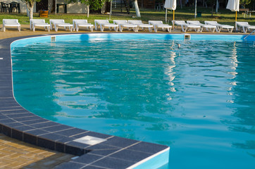 Pool view and sun loungers. Summer relaxation by the pool.