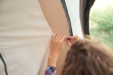 Woman setting up camping tent at the forest