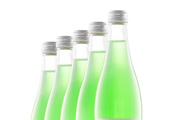 Transparent bottles of green lemonade stand in a row behind each other. Isolate