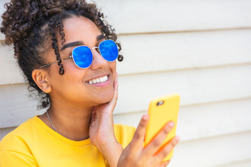 Girl teenager teen female young African American woman wearing sunglasses using cell phone