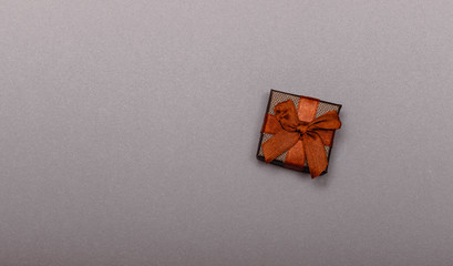 Fototapeta na wymiar One gift wrapped in dark grey paper with luxury bow on dark background. Top view with copy space for text.