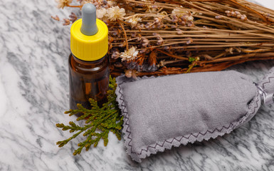 Essential oil and lavender flowers. Selection of essential oil on marble tabel with various organic herbs and flowers in the background.