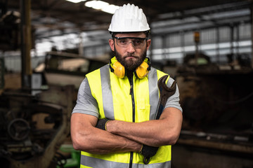 Portrait of technician man or industrial worker with hardhat or helmet, eye protection glasses and vest working electronic machinery on laptop and mechanical  in Factory of manufacturing place