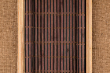 Two bamboo mat with curled edges lie on sacking.