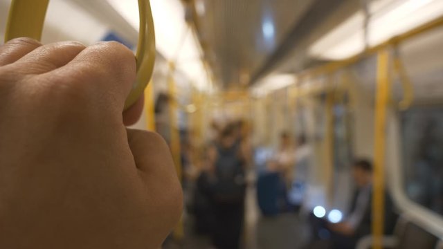 A close up view of someone&rsquo;s hand holding a strap in a train.