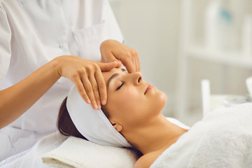 Obraz na płótnie Canvas Woman face massage. A professional beautician makes massage treatments for a client in a beauty salon.
