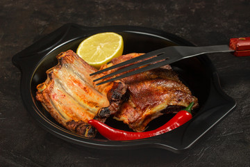 Baked pork ribs with lemon and hot pepper and a barbecue fork