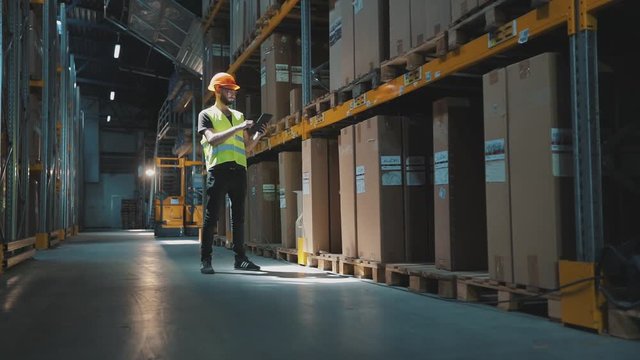 Warehouse manager of a large factory. A manager with a tablet in a warehouse checks the goods