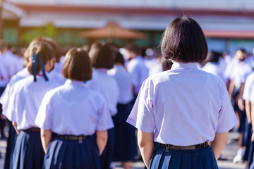 Asian hight school white uniform students stand in line to show respect for their national anthem...