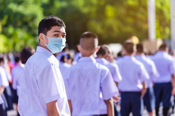 Asian male high school student in white uniform on the semester start wearing masks during the Coronavirus 2019 (Covid-19) epidemic.