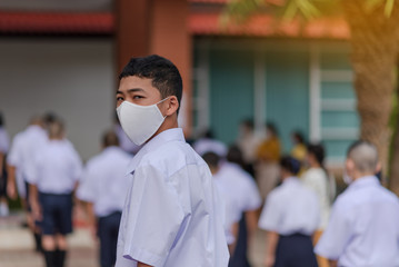 Fototapeta na wymiar Asian male high school student in white uniform on the semester start wearing masks during the Coronavirus 2019 (Covid-19) epidemic.