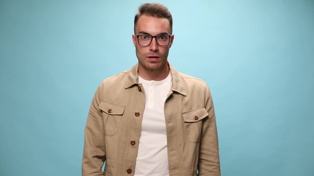 attractive casual guy making worries, being shocked, slapping his face, puffing cheeks and can't explain what's happening on blue background