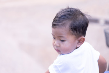 Asian boy wearing a white shirt looking back