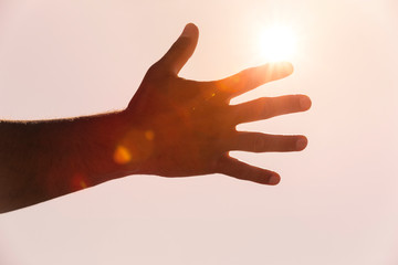 Männerhand im Gegenlicht mit Sonnenstrahlen