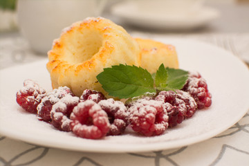 Curd muffins with raspberries and mint on a white ceramic plate.
