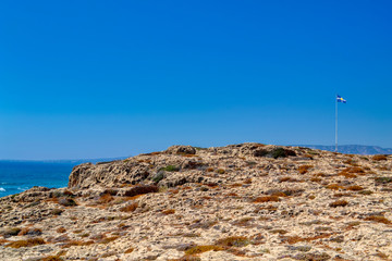Fototapeta na wymiar Rocks on the sea coast in the city of Paphos, Cyprus. View of the yellow sand and stone cliffs with shallow desert vegetation.